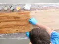 Mani guantate applicano un trattamento per come indurire il legno. Tavolo in legno con diverse lattine di finitura.