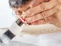Un uomo applica il primer per legno con un pennello, preparando la superficie per la verniciatura.