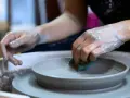 Mani sporche di argilla lavorano su un piatto al tornio, creando forme uniche con lavori con argilla senza cottura.