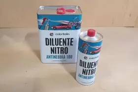 Due barattoli di diluente nitro Coloritalia, uno da 5 litri e uno da 1 litro, con grafica di auto e bici. La differenza tra diluente sintetico e nitro è nella composizione.
