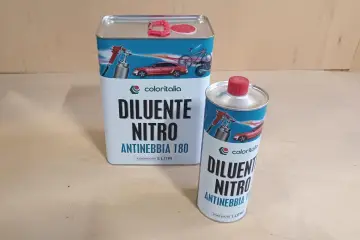 Due barattoli di diluente nitro Coloritalia, uno da 5 litri e uno da 1 litro, con grafica di auto e bici. La differenza tra diluente sintetico e nitro è nella composizione.
