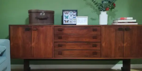 Mobile legno scolorito con cassetti e ante, decorato con una valigia vintage, cornici con farfalle e un vaso di fiori.